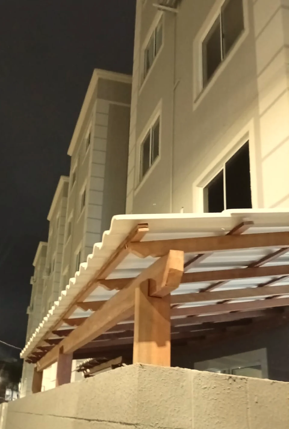 Cobertura de telhas claras com estrutura de madeira vista à noite